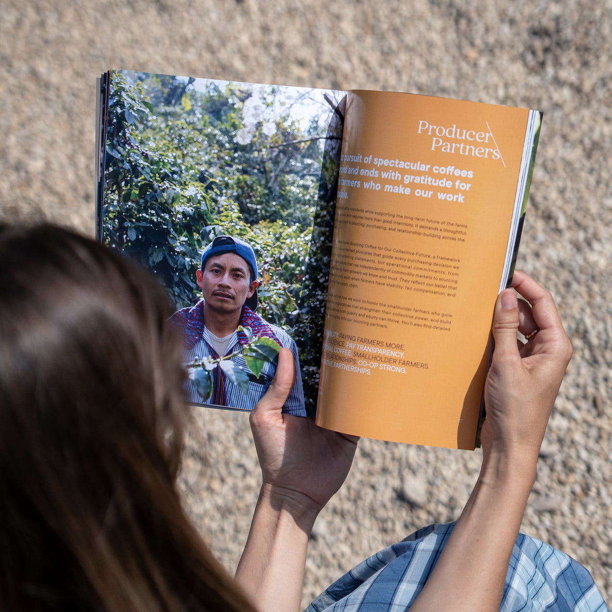 Person holding a book open to a page with a coffee farmer and text about Producer Partners.