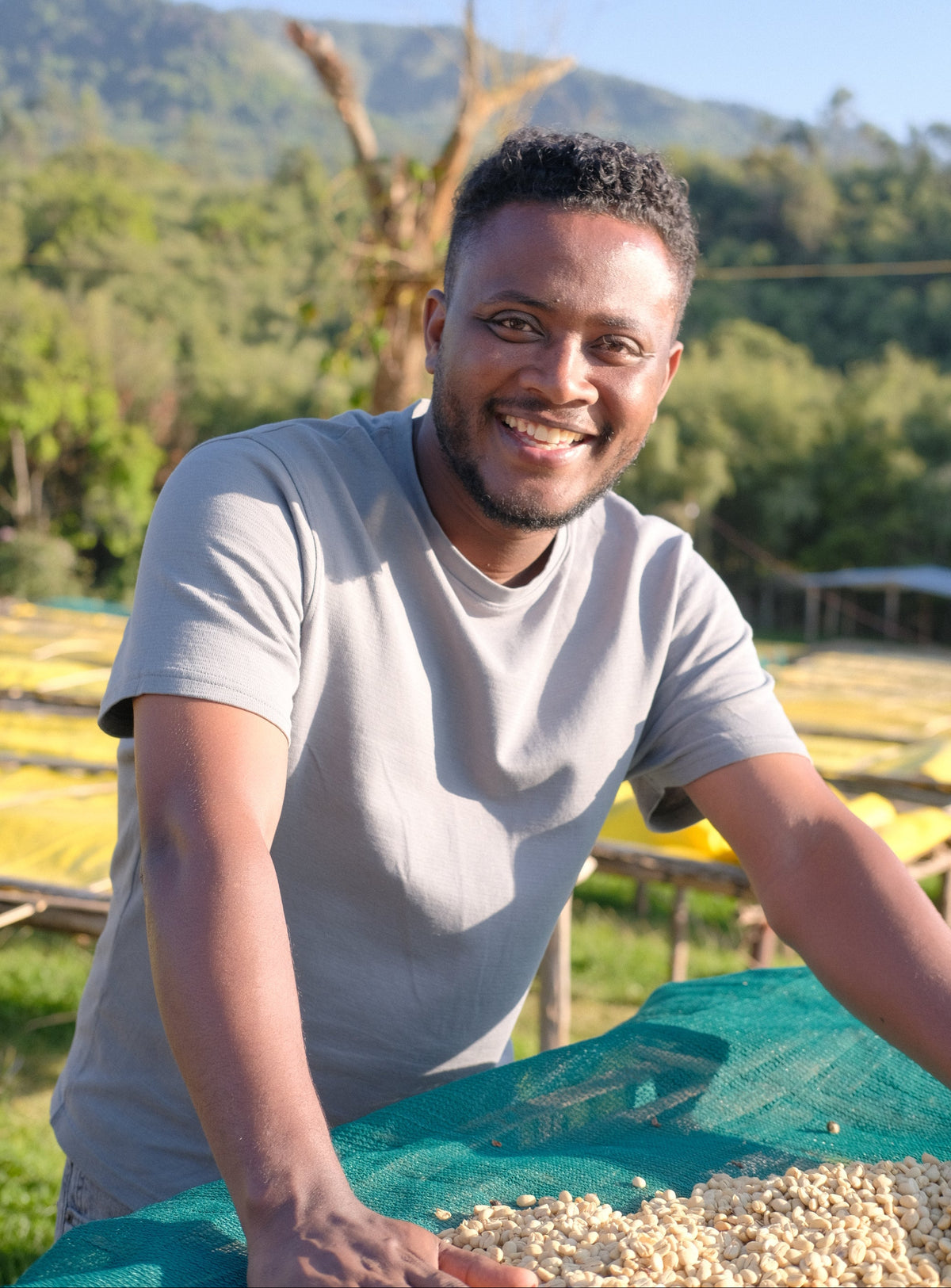 Tamiru Tadesse smiles near a drying bed with coffee.